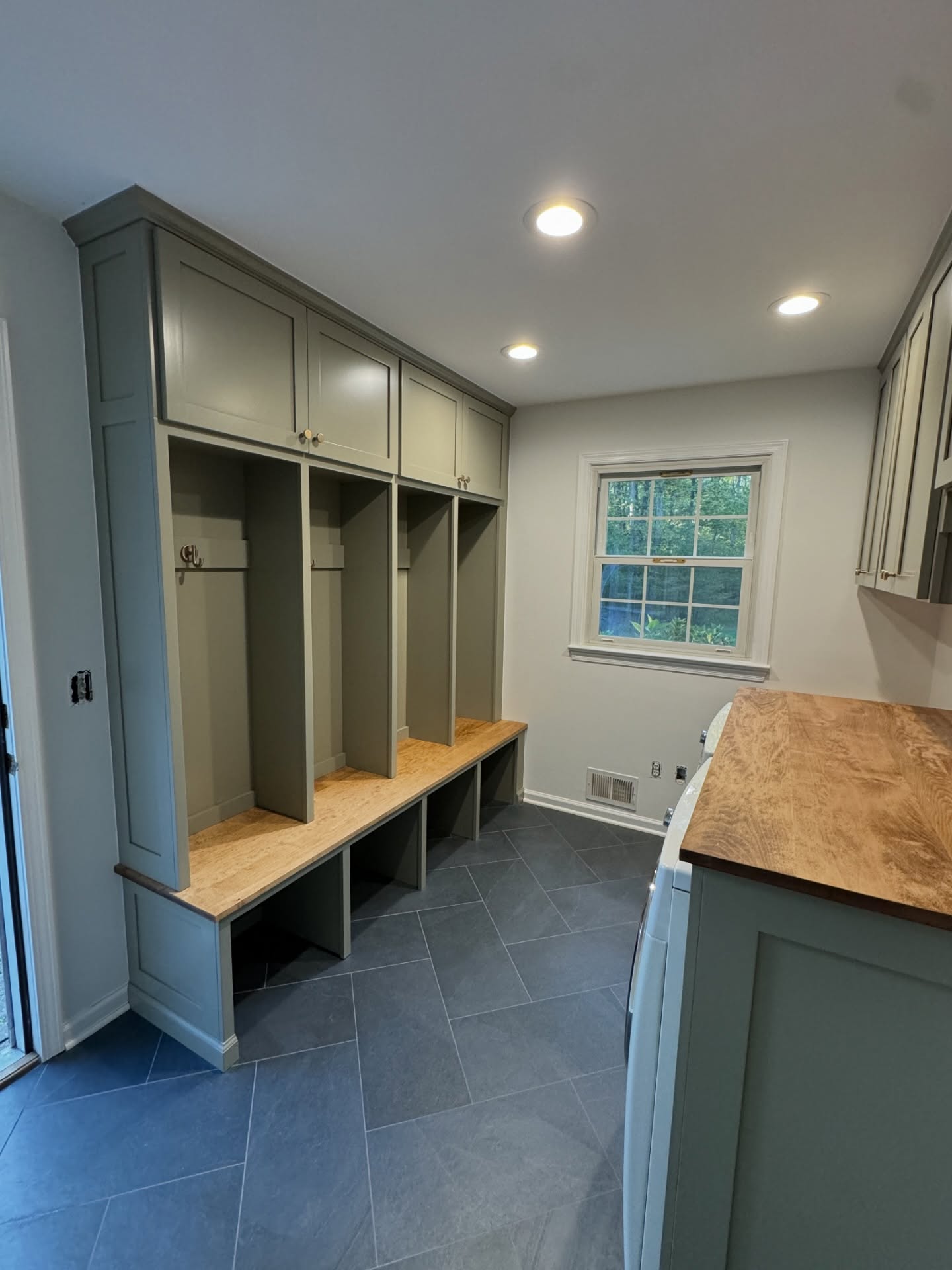 Mudroom and laundry room with green lockers, butcher block counter and slate tile