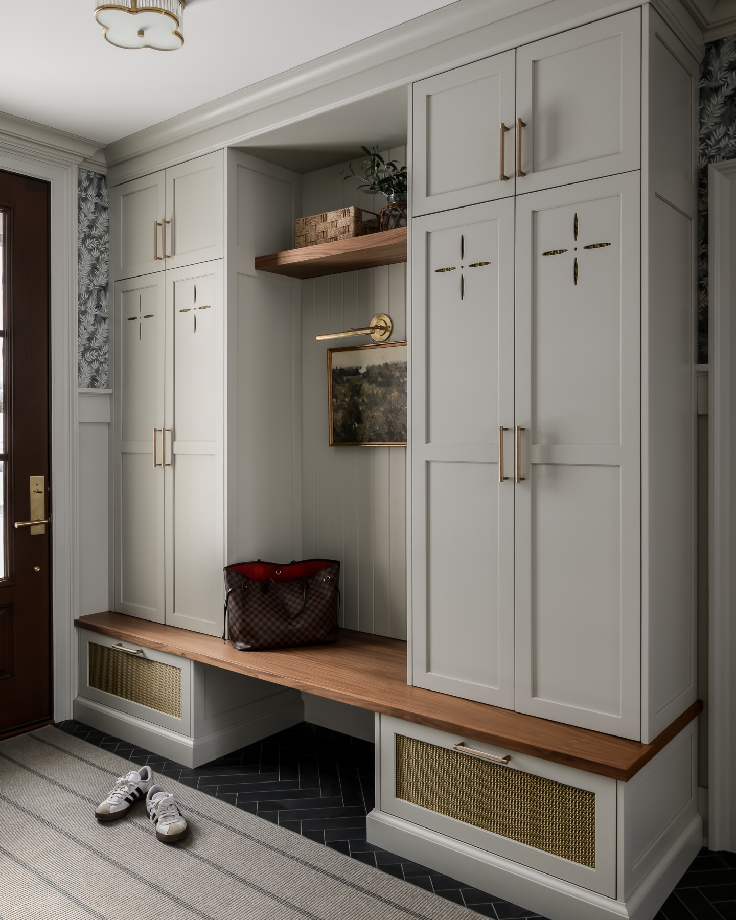 Custom gray mudroom cabinetry with walnut bench and brass mesh drawer fronts